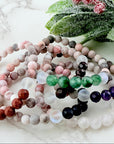 Set of beaded bracelets on a white surface with greenery in the background