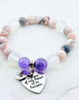 Beaded bracelet with purple heart charm and engraved message on a light background