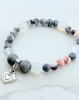 Beaded bracelet with a heart charm on a marble surface