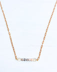 Necklace with small beads on a gold chain against a white background