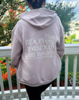 Person wearing a hoodie with 'Bloom Where You Are Planted' text on a balcony.