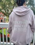 Person wearing a light pink hoodie with text on the back, standing outdoors.
