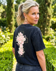 Woman wearing a black t-shirt with floral designs outdoors