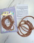 Set of beaded hair ties with packaging and instructions on a marble surface