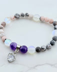 Beaded bracelet with purple charm on a marble surface