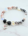 Beaded bracelet with a heart charm on a marble surface