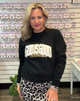 Woman wearing a black sweatshirt with gold saying God is Good all the time text in a store setting