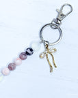 Keychain with beads and a gold bow charm on a white background