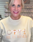 Woman wearing a light-colored sweatshirt with 'He is Risen' text and images.