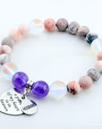 Multicolored beaded bracelet with heart and round charms on a white background
