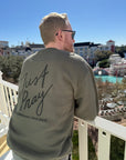 Man wearing a sweatshirt with 'Just Pray' text on a balcony overlooking a scenic area.