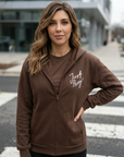 Woman wearing a brown hoodie with 'Just Pray' text in an urban setting