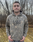 Person wearing a camouflage hoodie with 'Praise the Lord' text outdoors.