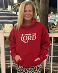 Woman wearing a red hoodie with 'PRAISE THE LORD' text in an outdoor setting.