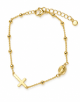 A gold chain bracelet featuring a cross pendant, a small oval religious medallion, and polished gold bead accents, displayed on a clean white background.