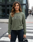 Woman wearing a green sweatshirt with 'Praise the Lord' text on a city street.