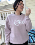 Person wearing a pink sweatshirt with 'Praise the Lord' text on a porch.