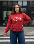 Woman wearing a red hoodie with 'Praise the Lord' text on a city street.
