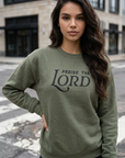 Woman wearing a green sweatshirt with 'Praise the Lord' text on a city street.