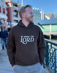 Man wearing a hoodie with 'Praise the Lord' text standing on a boardwalk.