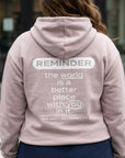 Person wearing a light pink hoodie with a motivational message on the back.