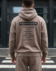 Person wearing a beige hoodie with a motivational message on the back, standing on a zebra crossing.