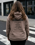 Person wearing a hoodie with a motivational message on the back, standing on a street.