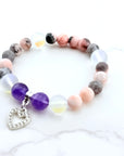 Multicolored beaded bracelet with a heart charm on a white background