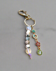 A colorful keychain with a heart-shaped pendant, featuring a mix of beads and a crystal-like star charm, displayed on a wooden surface.