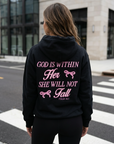 Person wearing a black hoodie with a motivational quote on the back, standing on a street.