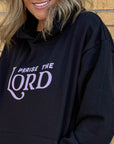 Person wearing a black hoodie with 'Praise the Lord' text against a brick wall.