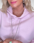 Person wearing a pink hoodie with text on it, holding a bracelet.