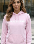 Woman wearing a pink hoodie with 'Rust in God' text outdoors.