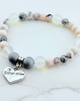 Beaded bracelet with a heart-shaped 'Sister in Law' charm on a white marble background