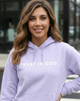 Woman wearing a purple hoodie with 'Trust in God' text.