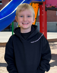 Young boy wearing a black hoodie with text on a playground
