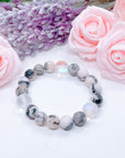 The original 5 Second Rule gemstone stretch bracelet made with pink zebra jasper beads and translucent aura beads sits on a white table. Natural neutral colors.