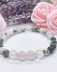 The Rose Quartz Companion Gemstone stretch bracelet made with 2 pink rose quartz gemstones, translucent aura beads, and pink jasper gemstones sit on a white table.