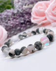 The 5 Second Rule Companion gemstone stretch bracelet made with pink zebra jasper beads and translucent aura beads sits on a white table. Natural neutral colors.