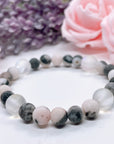 The 5 Second Rule Companion gemstone stretch bracelet made with pink zebra jasper beads and translucent aura beads sits on a white table. Natural neutral colors.