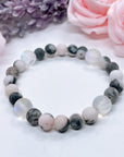 The 5 Second Rule Companion gemstone stretch bracelet made with pink zebra jasper beads and translucent aura beads sits on a white table. Natural neutral colors.