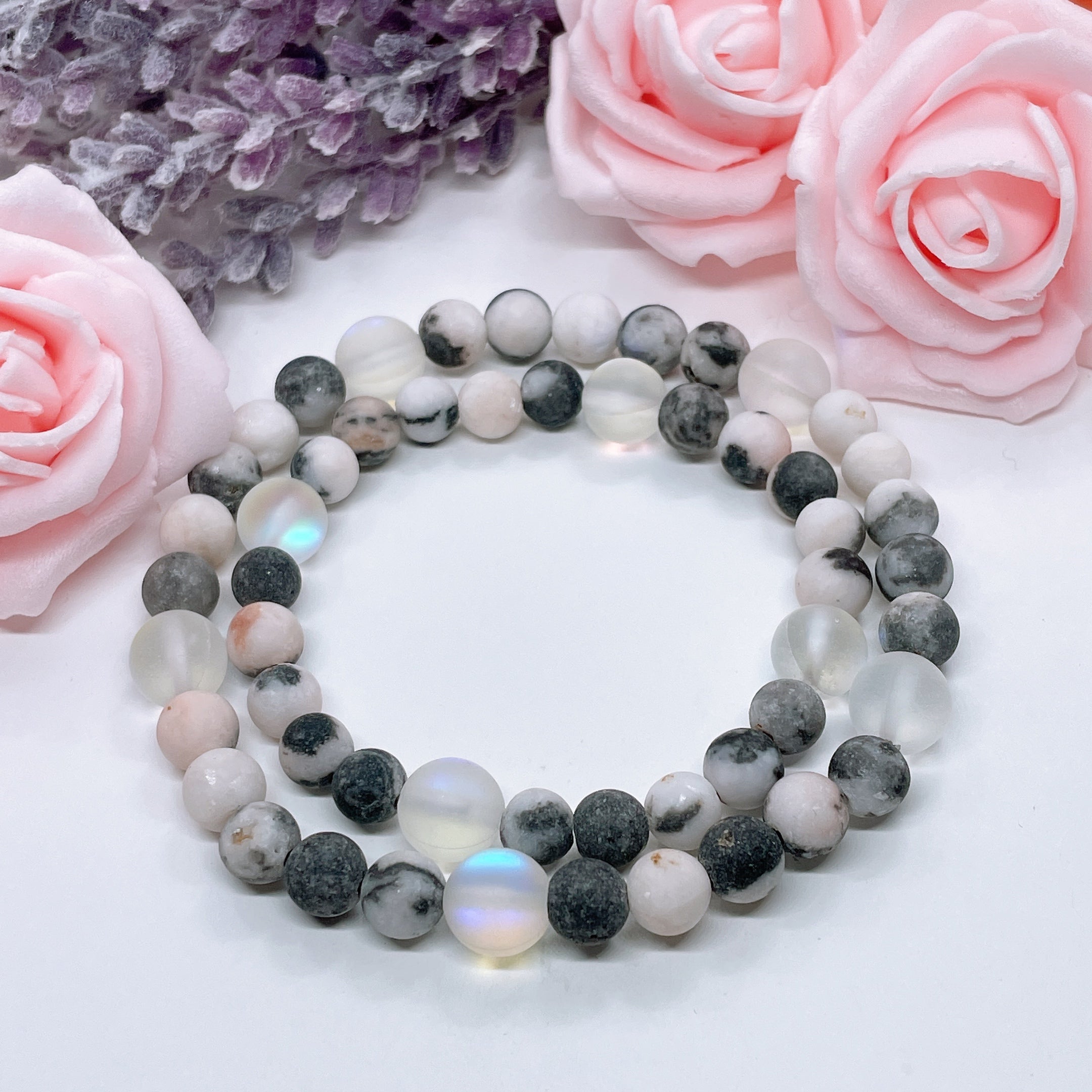 The 5 Second Rule Companion gemstone stretch bracelet made with pink zebra jasper beads and translucent aura beads sits on a white table. Natural neutral colors.