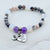 Beaded bracelet with heart-shaped charm and engraved text on a marble background