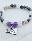 Beaded bracelet with heart-shaped charm and engraved text on a marble background