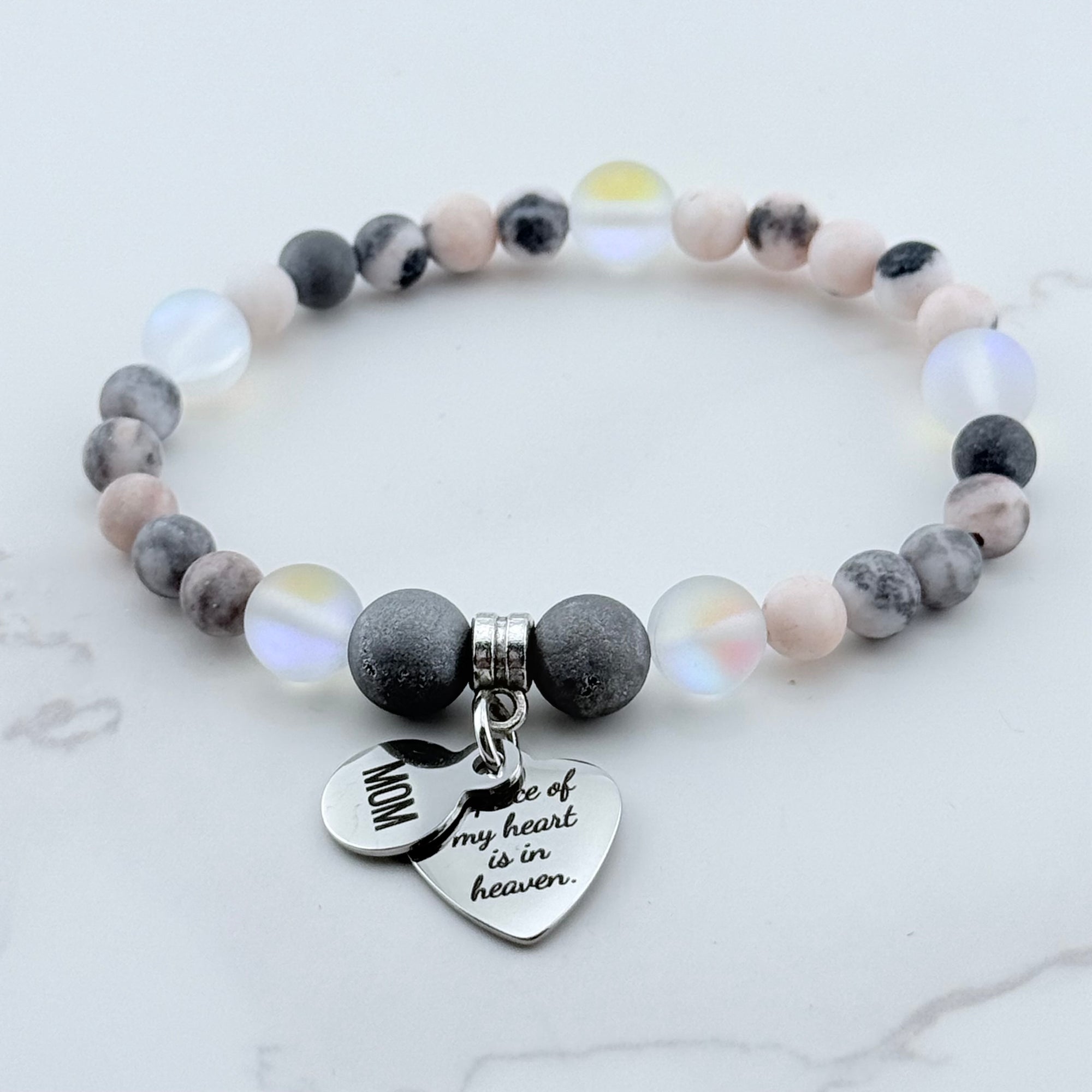 Beaded bracelet with heart-shaped charms on a marble surface