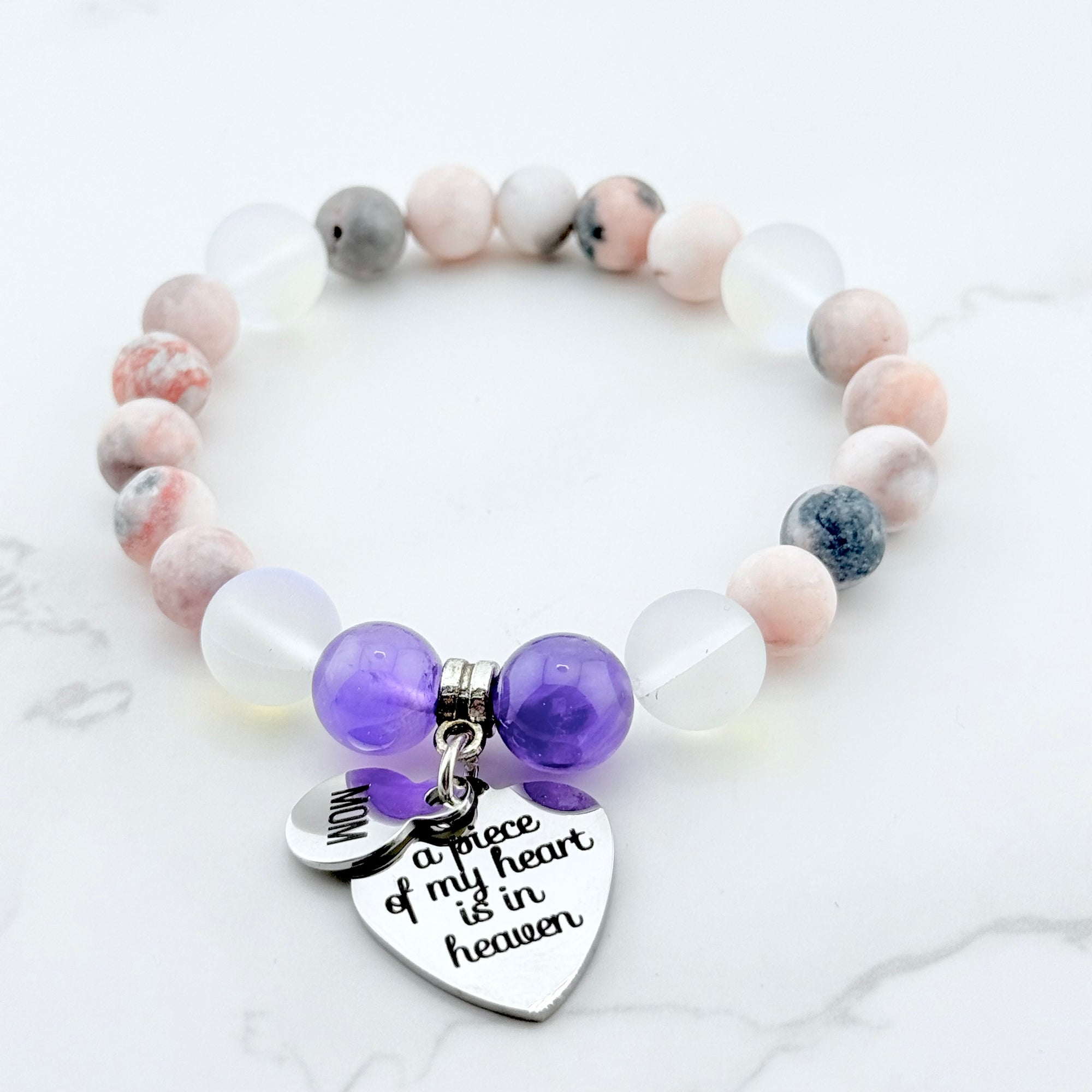 Beaded bracelet with purple heart charm and engraved message on a light background