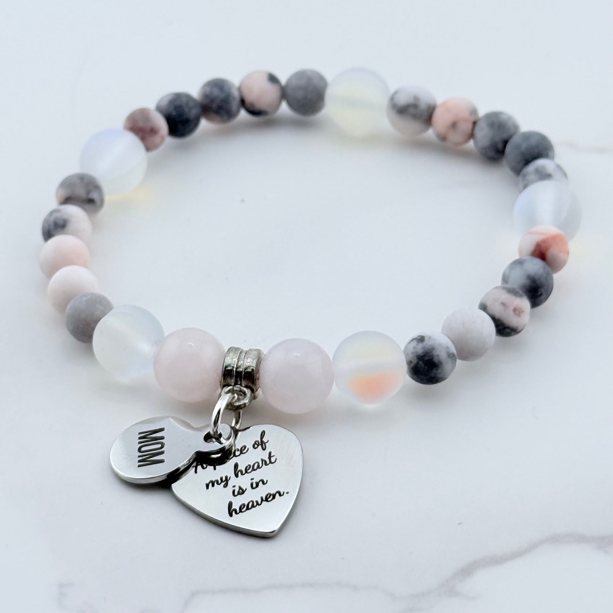 Beaded bracelet with heart-shaped charm on a marble surface