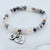 Beaded bracelet with heart-shaped charm on a marble surface