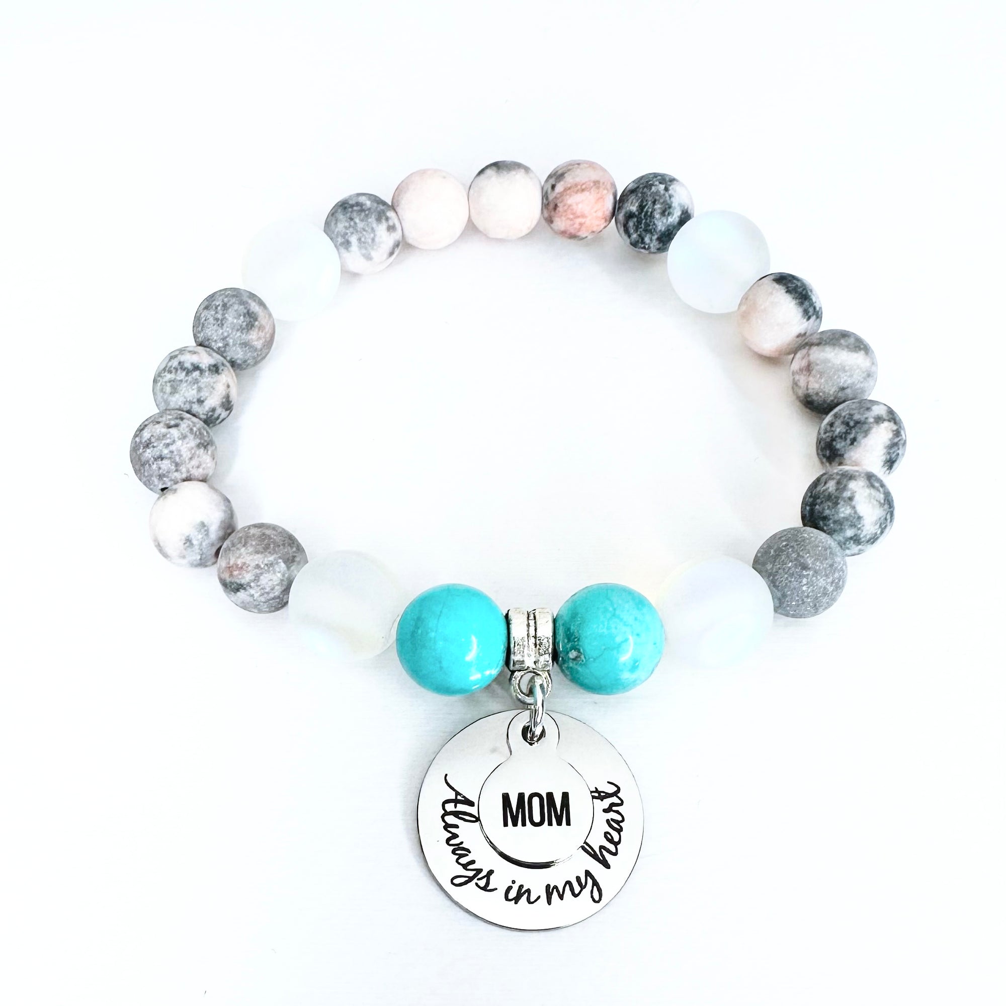 Beaded bracelet with turquoise charm and 'Mom always in my heart' tag on a white background