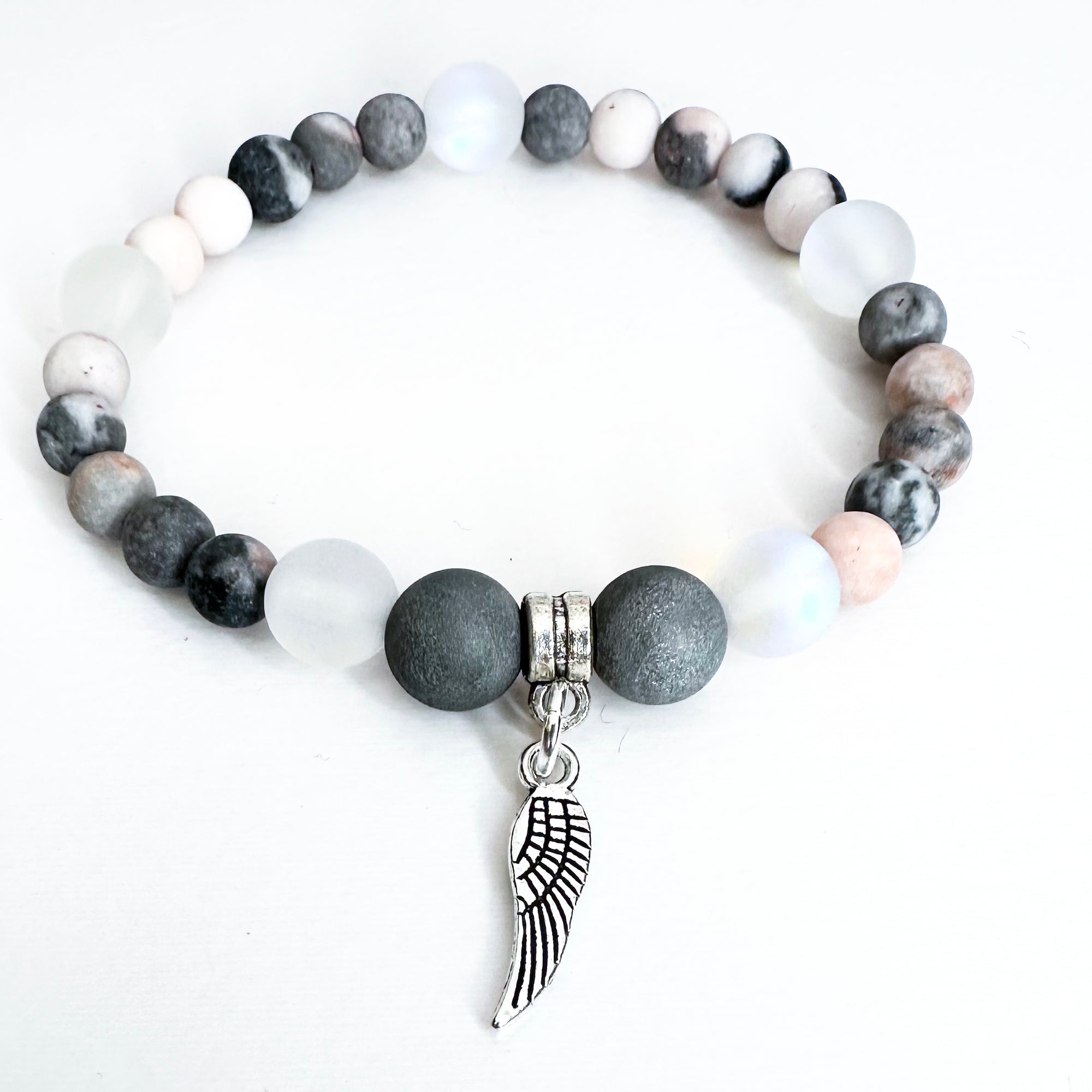 Bracelet with gray and white beads and a silver wing charm on a white background